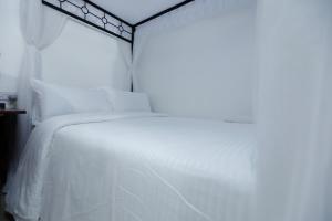a white bed with white sheets and a window at Self Contained Studio in Nakuru