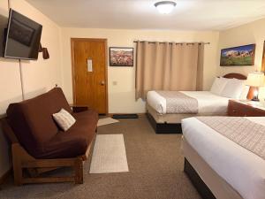 a hotel room with two beds and a chair and a television at Whitetail Creek Resort in Lead