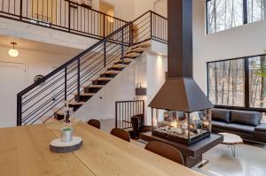 a living room with a fireplace and a staircase at Pur Nature et Spa Eastman in Eastman +26 photos