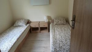 a small room with two beds and a night stand at Domek letniskowy Pod Topolami in Sieraków