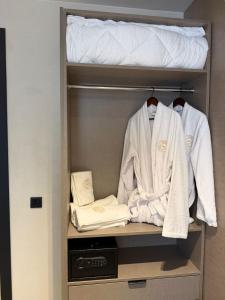 a closet with white robes and a bed at Fron Hotel in Prishtinë