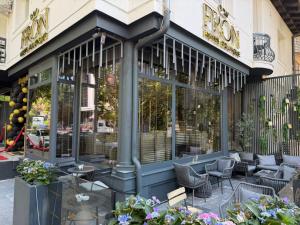 a cafe with chairs and tables in front of a building at Fron Hotel in Prishtinë