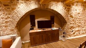 a living room with a tv and a brick wall at Casa Stratigos in Corfu