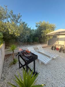 a patio with two white chairs and a table and a grill at Vacation rooms in Vlorë