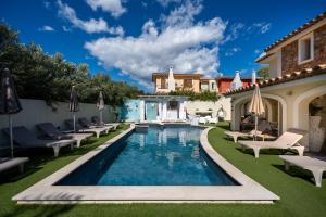 una piscina in un cortile con sedie e una casa di Suimi's Hotel a Villasimius