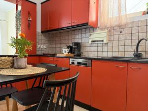 a kitchen with red cabinets and a table with chairs at Lemon Tree Apartment in Chios