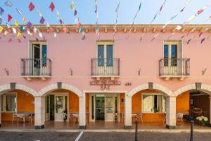 a pink building with arches and flags at Hotel Del Corso in Pula