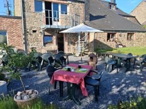 a patio with tables and chairs and an umbrella at B&B Les Trois Voisins in Bourseigne-Vieille