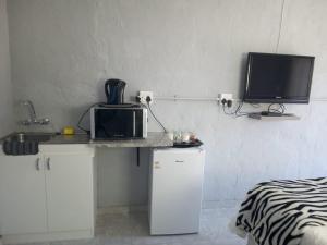 a kitchen with a counter with a microwave and a tv at JJM Accommodation in Keetmanshoop
