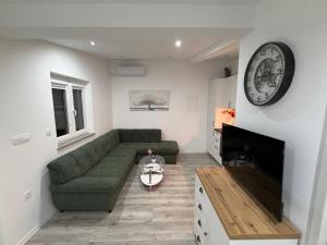 a living room with a couch and a clock on the wall at Apartments and rooms Bova in Baška