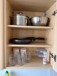 a cupboard with dishes and bowls and a pan at Gemütlicher Aufenthalt mit Netflix & perfekter Anbindung! in Elmshorn
