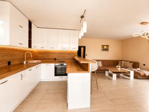 a kitchen with white cabinets and a living room at Къща за гости ЕМ Парадайс in Tserova Koriya