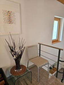 a chair and a glass table with a vase of flowers at Cà ai Camòss, DUPLEX deluxe - centro paese in San Bernardino