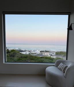 a living room with a large window with a chair at Atlantic Corner in Yzerfontein