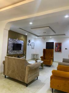 a living room with couches and a tv and chairs at Hollysee Hotel & Suites in Baruwa