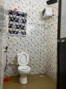 a bathroom with a white toilet in a room at Hollysee Hotel & Suites in Baruwa