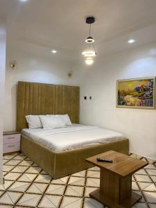 a bedroom with a large bed and a table at Hollysee Hotel & Suites in Baruwa