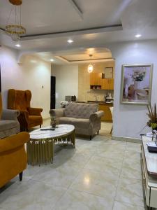 a living room with couches a table and a kitchen at Hollysee Hotel & Suites in Baruwa