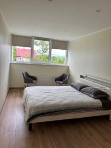 a bedroom with a large bed and two chairs at Miera osta in Salacgrīva