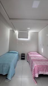 two beds in a room with white walls at Apartamento do Sol in Diamantina