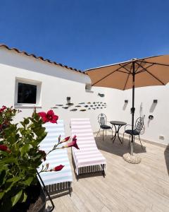 a patio with a table and chairs and an umbrella at Frida Luxury B&B in Vietri sul Mare