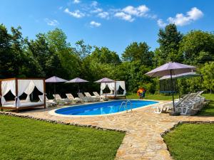 a pool with chairs and umbrellas in a yard at Къща за гости ЕМ Парадайс in Tserova Koriya