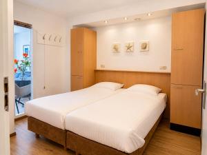 a bedroom with a large bed and a closet at Prins Prachtig Amelander Kaap 97 in Hollum