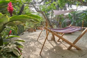 a hammock and chairs on the sand in a garden at HIDDEN HOSTAL MONTANITa in Montañita