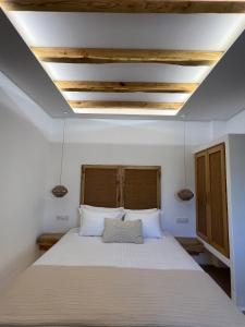 a bedroom with a bed with white sheets and wooden ceilings at Pyrgianos Suites - Private Plunge Pool in Naxos Chora