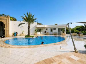 a large swimming pool with people in it at Residence Golden Beach au bord de la mer in Bin Rhilouf