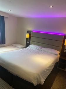 a bedroom with a large bed with purple lights on it at Wirral Park Hotel in Greasby