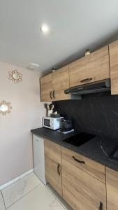 a kitchen with wooden cabinets and a black counter top at La Parenthèse in Sangatte