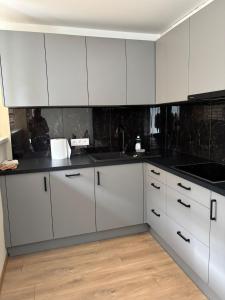 a kitchen with white cabinets and black counter tops at Miera osta in Salacgrīva