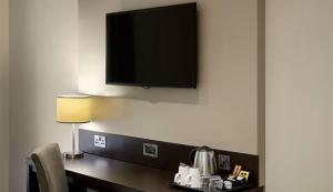a room with a desk with a television on a wall at Wirral Park Hotel in Greasby