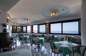 a restaurant with green tables and chairs and windows at Hotel Residence - Parco Mare Monte in Casamicciola Terme