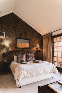 a bedroom with a large bed with a stone wall at Garingboom Guest Farm in Groot-Suurfontein