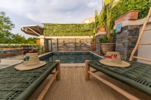 two straw hats sitting on benches next to a swimming pool at Riad Secret Mahjouba in Marrakesh