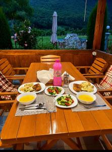 a wooden table with plates of food on it at Breti's GuestHouse in Vusanje +32 photos