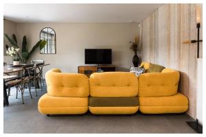 a living room with a yellow couch and a table at L'Aurore Céleste in Aywaille
