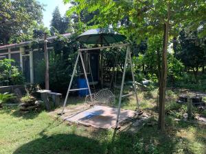 a swing with an umbrella in a yard at Mangifera Cabin in Kanchanrup in Kanchanpur