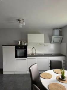 a kitchen with white cabinets and a table with chairs at Sweethome - Köln Messe in Bergisch Gladbach