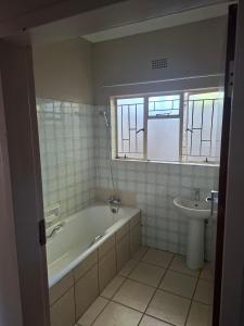 a bathroom with a bath tub and a sink at Oolele BnB Newcastle in Newcastle