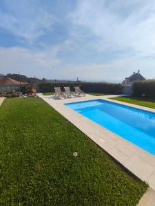 a swimming pool with lounge chairs next to a yard at Santiago 2 in Castelo do Neiva