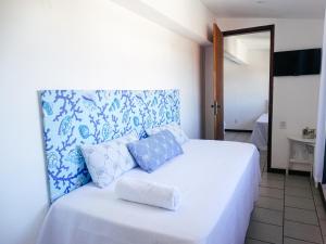 a bedroom with a white bed with blue pillows at Viva Buzios in Búzios