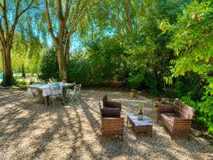a patio with a table and chairs and trees at Gîte Moulin de l'Anet in Goult