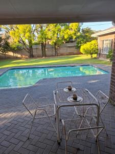 a table and chairs next to a swimming pool at Oolele BnB Newcastle in Newcastle