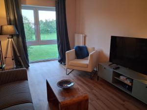 a living room with a couch and a television and a chair at Landliebe in Blomberg