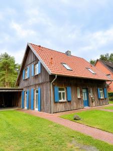 a wooden house with a red roof at Ferienhaus an der Lohheide in Walsrode