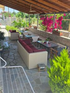 a patio with a couch and tables and flowers at Anemoni apartment Asprovalta in Asprovalta