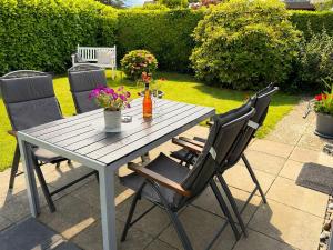 a wooden table with two chairs and flowers on a patio at Zwischen Schlei & Ostsee in Kappeln